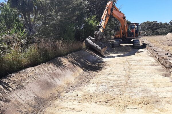 Excavator carrying out land excavation and earthworks for a wastewater treatment system upgrade, showing civil construction contractors completing deep drainage and stormwater drainage work as part of wider civil engineering in Canterbury.