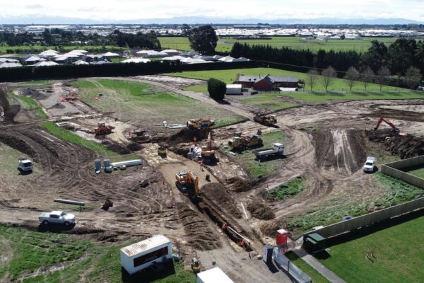 Large-scale subdivision earthworks and civil work with multiple excavators completing stormwater drainage system installation, wastewater treatment network extensions, and preparation for future roading and construction projects.