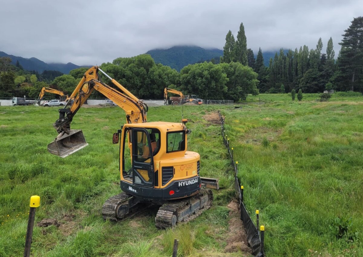 Excavator completing land excavation and trenching for storm water reticulation, wastewater reticulation system installation, and subdivision earthworks for a civil engineering project.