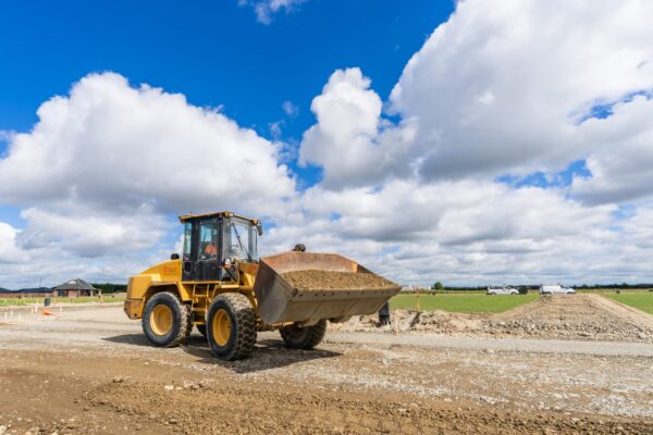 A wheel loader moves freshly placed material across the subdivision site, supporting smooth earthworks and site preparation for the Rolleston development.