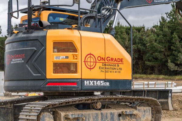 Close-up branding on the excavator highlights On Grade’s commitment to high-quality earthworks and excavation across Canterbury.