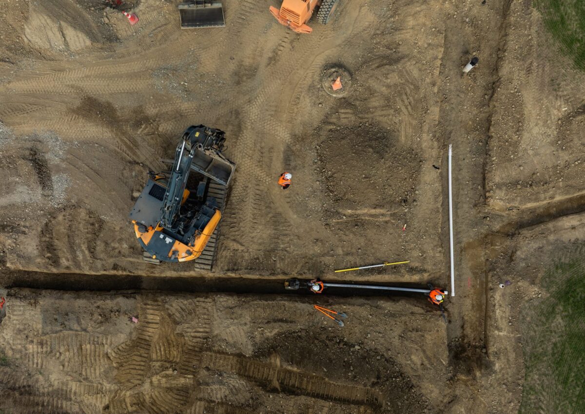Overhead image of civil contractors installing Water Reticulation Systems and stormwater drainage pipes during land excavation, forming part of deep drainage and storm water solutions across new subdivision streetscapes.