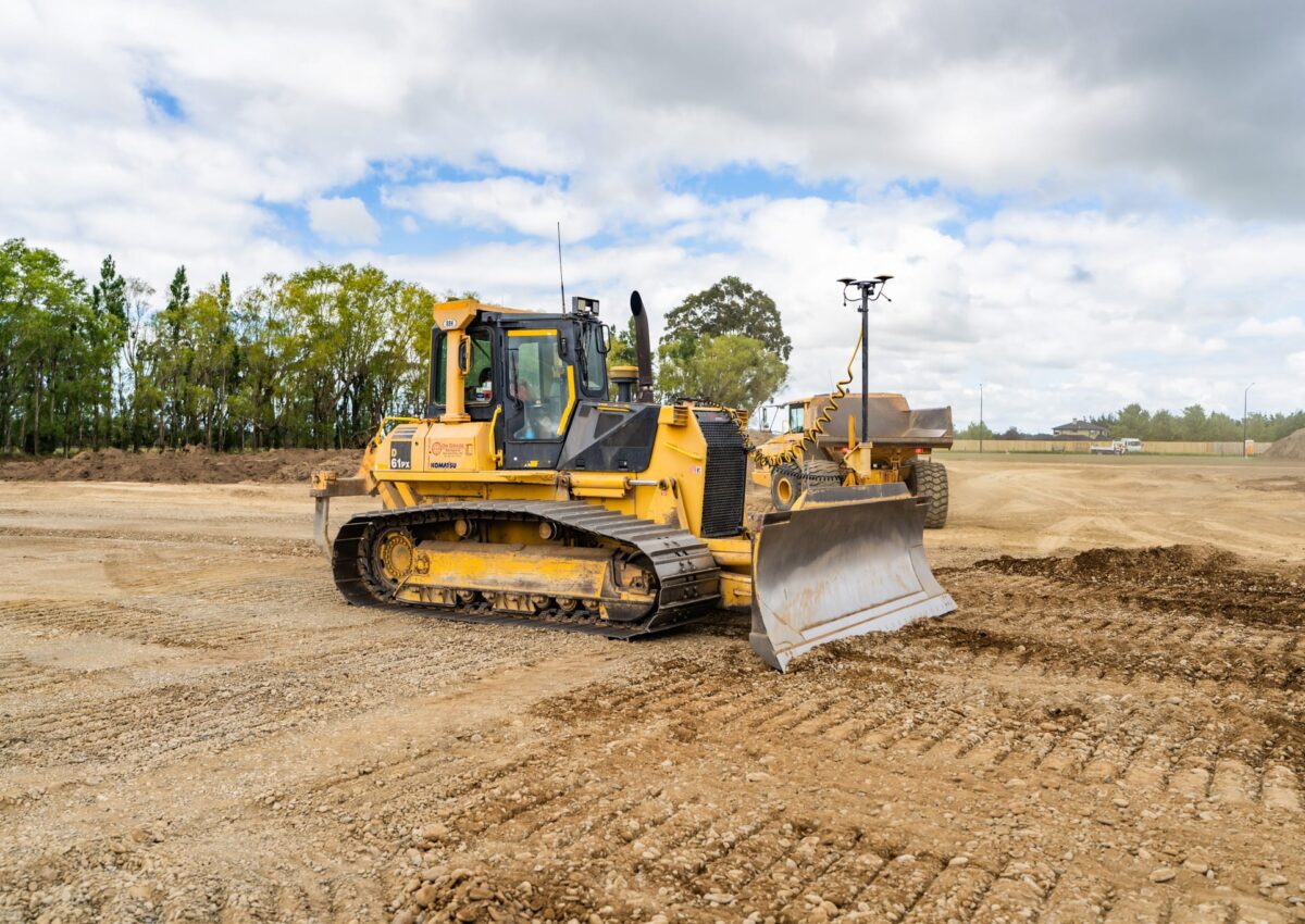 A bulldozer trims and levels the surface, guided by GPS to keep the final grade exactly where it needs to be.