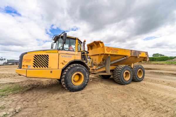 A Volvo dump truck stands ready for another load, part of the fleet supporting large-scale bulk earthworks on site.