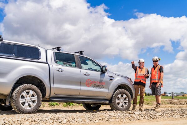 Hands reviewing printed subdivision plans showing storm water drainage systems, wastewater treatment layouts, water reticulation networks and civil engineering design.