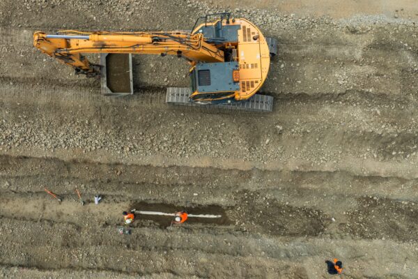 Overhead image of an excavator and civil construction crew carrying out land excavation and deep drainage for storm water solutions, wastewater treatment connections and water reticulation systems on a large civil engineering Christchurch project.