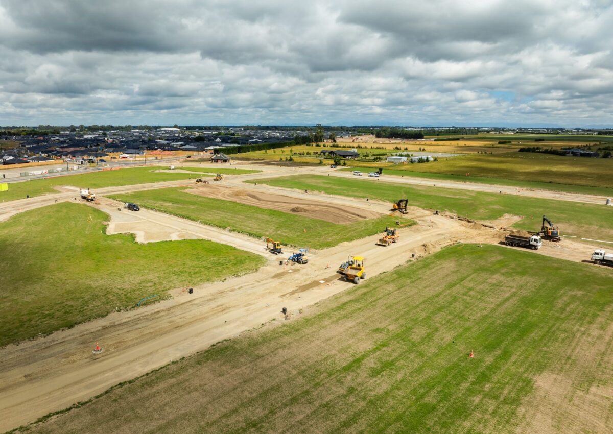 Wide aerial view of subdivision earthworks, roading and civil construction works including excavations, storm drain installation, water reticulation, stormwater systems and future footpaths undertaken by a civil engineering company and earthworks contractor.