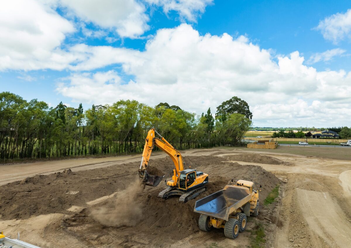 Aerial view of heavy machinery completing earthworks, roading formation and stormwater drainage for a development site, with civil contractors preparing land for wastewater treatment infrastructure and storm water reticulation.