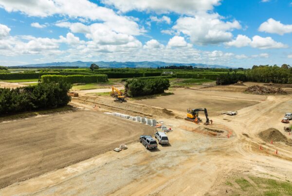 A wide view of subdivision earthworks with excavations, civil construction machinery and civil contractors preparing land for stormwater drainage, water reticulation and wastewater treatment systems as part of large construction projects managed by a civil engineering company and construction contractor in Canterbury.
