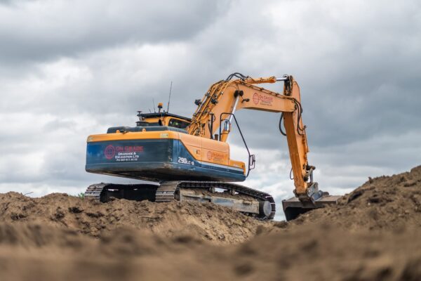 A large excavator undertaking land excavation and civil work for storm water drainage, kerb and channel preparation, wastewater reticulation and water treatment infrastructure led by Christchurch civil contractors.