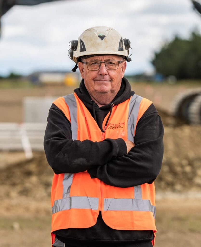 Construction team member on a civil construction site wearing safety gear, showcasing earthworks company services including subdivision earthworks, stormwater drainage, sanitary sewer pump stations, wastewater treatment, water reticulation and civil work.