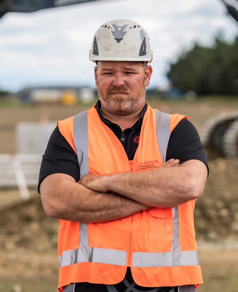 Civil construction worker in high-vis vest and helmet standing on site, highlighting stormwater drainage systems, sewage treatment plant work, wastewater treatment plant support, stormwater reticulation, roading and land excavation by civil contractors.