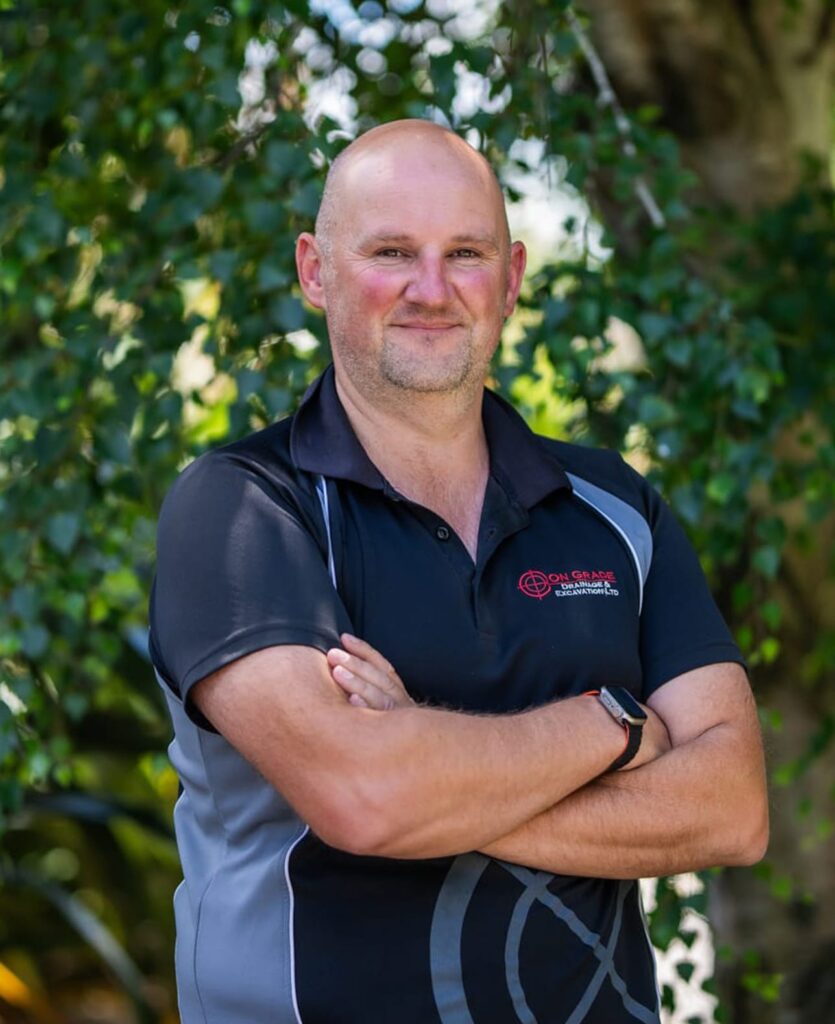Team member from a civil engineering company standing outdoors in branded workwear, representing civil construction, excavations, land excavation, stormwater drainage, wastewater treatment systems, water reticulation and local earthworks for subdivision earthworks and construction projects.