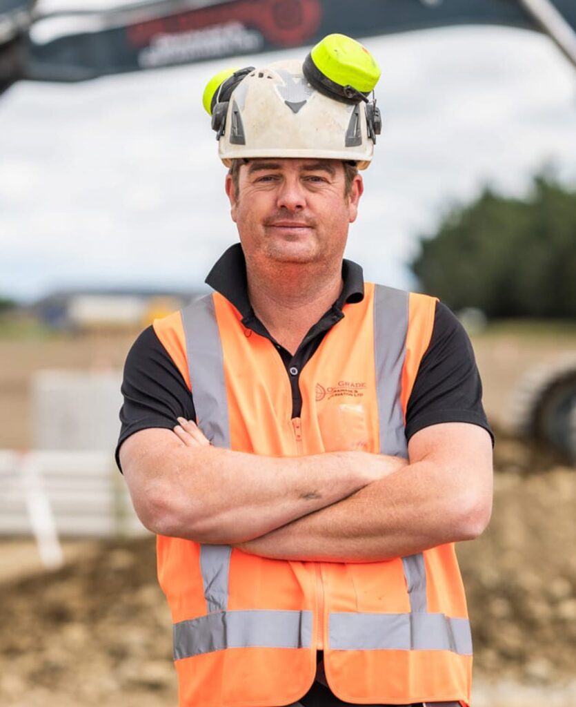 Construction contractor wearing high-vis gear and helmet on a worksite, showcasing civil construction, deep drainage, storm drain installation, stormwater systems, wastewater treatment plant services and earthworks company capability in Christchurch.